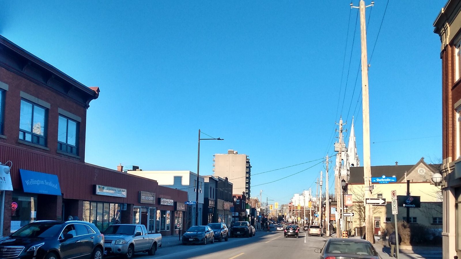 Low-rise storefronts and traffic on Wellington Street West, one of Ottawa's traditional main streets