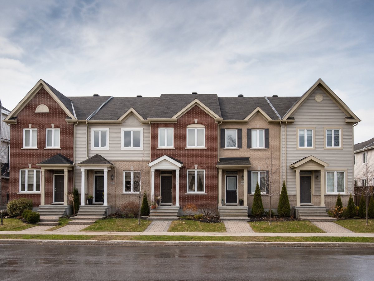 Row of brick townhouses with individual front doors, small front gardens and steps to the sidewalk